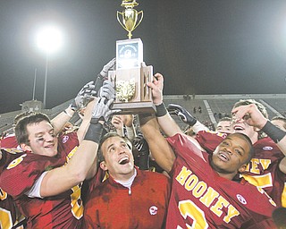 Members of the Cardinal Mooney football team, including (from left) seniors Cameron DiVito, Joe Deniro (6), coach P.J. Fecko and Roosevelt Griffin (3) hold the Division III state championship trophy following the Cardinals’ 21-14 win over Springfield Shawnee at Fawcett Stadium in Canton.