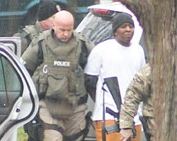 A SWAT team member leads Kevon Williams, 20, out of his Ohio Avenue home after a lengthy standoff with police.