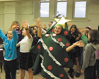 For the third year in a row, girls from Holy Family School’s Acts of Random Kindness Club (ARK) sang at the annual holiday meal served at the Immaculate Conception-Sacred Heart of Jesus soup kitchen on Youngstown’s East Side. Alena Argiro, grade 7, is dressed as the joyous Christmas tree. As the club performed, visitors were served a meal, various desserts and a beverage.