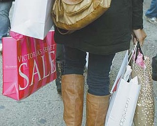 A woman walks down 34th Street carrying the fruits of her shopping expedition on the day after Christmas in New York. A flurry of post-Christmas bargain-shopping helped drive sales higher in the last week of December, according to a report Wednesday from a shopping-mall trade group.