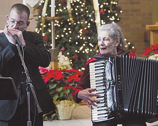 The Rev. Michael Marcelli of St. Charles Church, Boardman, performs Christmas music on his harmonica, accompanied by accordionist Betty Bannon during a Christmas music concert Sunday at the church.