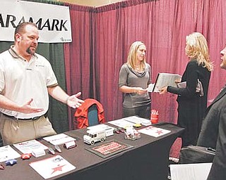 Aramark service managers Randy Nelson, left, and Brittany Howard, center, talk to job-seekers Tuesday at the HireLive career fair in Los Angeles. More people sought unemployment benefits last week as companies let go of thousands of workers hired for the holiday season.