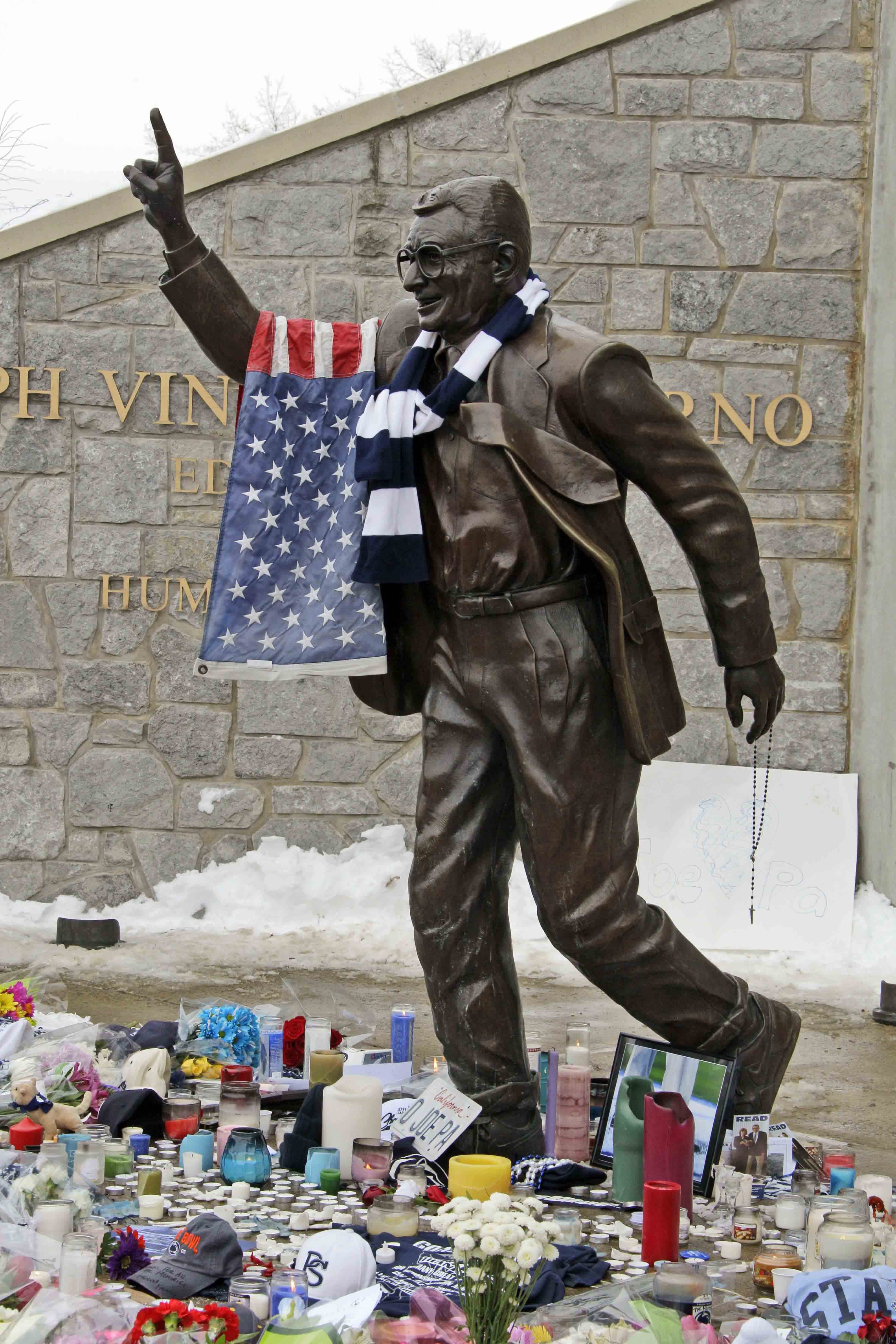 A flag and Penn State scarf were placed on a statue of Joe Paterno outside Beaver Stadium on the Penn State University campus by fans paying their respects after learning of his death Sunday, Jan. 22, 2012 in State College,Pa.. (AP Photo/Gene J. Puskar)