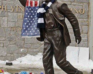 A flag and Penn State scarf were placed on a statue of Joe Paterno outside Beaver Stadium on the Penn State University campus by fans paying their respects after learning of his death Sunday, Jan. 22, 2012 in State College,Pa.. (AP Photo/Gene J. Puskar)