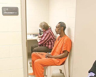 Mahoning County Deputy Sheriff Stephanie Harchar stands guard as Artis Walton is video-arraigned from the county jail on a criminal-trespass charge. Brenda Rider, sitting next to Walton, is a Youngstown Municipal Court bailiff who took notes. Walton, who pleaded innocent, was one of seven inmates to be video-arraigned Monday.