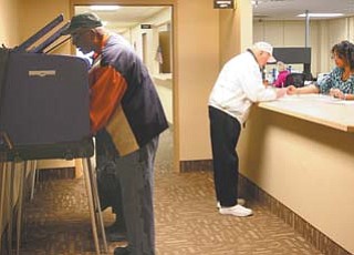 Early voting in Ohio is under way. Hugh Dillard, front left, and his wife, Mary, voted Tuesday, the first day to cast early ballots, at the Mahoning County Board of Elections office at the Oakhill Renaissance Center in Youngstown. Ann Simms, right, an elections employee, helps a man, who declined to be identified, before he voted.