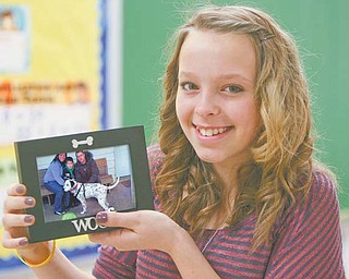 Maddi Graham, a seventh-grader at Akiva Academy in Youngstown, holds a picture of Dahlia the Dalmatian, who
needed a home after the death of her owners. The people in the photograph are Dahlia’s new owners.