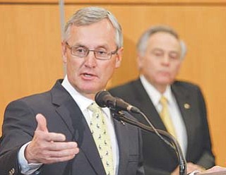 University of Akron president Luis M. Proenza, background, listens as former Ohio State football coach Jim Tressel addresses the media after being introduced as the university’s new vice president for strategic engagement at a press conference in Akron on Thursday.