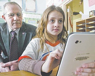 Third-grade teacher Ashley Wallace’s students at Lynn Kirk Elementary School in Austintown are using Samsung Galaxy tablets in class as part of a pilot program to test the device’s uses in the classroom. Angelina Diana, above, works on the Galaxy while school-board member Dave Schnurrenberger looks on. Two other district teachers — one at Austintown Middle School and one at Fitch High School — also are testing the tablets, Superintendent Vince Colaluca said.