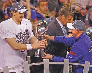 New York Giants head coach Tom Coughlin, right, hands the Vince Lombardi Trophy over to New York Giants quarterback Eli Manning after the Super Bowl XLVI in Indianapolis on Sunday. The Giants defeated the New England Patriots 21-17.