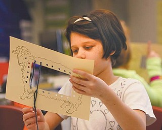 Delilah Lopez, a third-grader at Struthers Elementary School, shows how to make a loom.