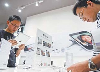 Customers try out iPads at an authorized Apple dealer outlet in Changsha in south China’s Hunan province. Authorities have seized iPads from more Chinese retailers in February in an escalating trademark dispute between Apple Inc. and a struggling local company that could disrupt global sales of the popular tablet computer.