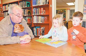 Bill Leskanic, left, of Boardman and his dog, Periwinkle, listen as Carli Hamilton, 7, and Cole Hamilton, 5, both of Boardman read to Periwinkle. They were taking part in Monday’s Tales for Tails gathering at the Canfi eld branch of the Public Library of Youngstown and Mahoning County.