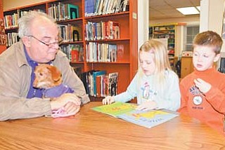 Bill Leskanic, left, of Boardman and his dog, Periwinkle, listen as Carli Hamilton, 7, and Cole Hamilton, 5, both of Boardman read to Periwinkle. They were taking part in Monday’s Tales for Tails gathering at the Canfi eld branch of the Public Library of Youngstown and Mahoning County.