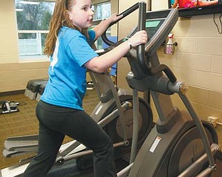 Katelyn Hutton, 9, of Lisbon watches the Disney Channel while using an elliptical at the Children’s Fitness Center at the Salem Community Center. The machines are designed for the smaller bodies of the 6-12 age group.