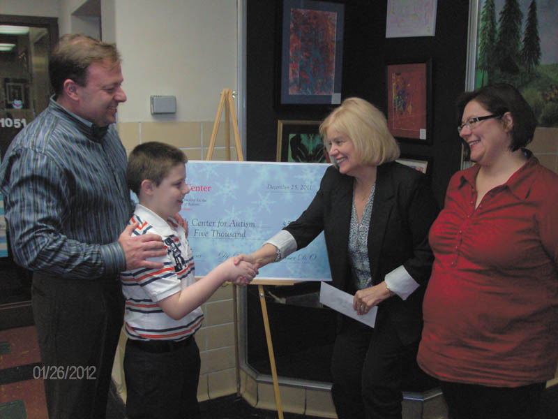 Dr. Douglas Musser, left, and his son, Robbie, collected $5,000 from people who enjoyed their elaborately decorated home this past December. An estimated 11,000 cars passed by the light display, which included a supersized Christmas tree, thousands of feet of lights, music and Santa in an upstairs window. Dr. Musser stationed friends and family near his street Dec. 23, 24 and 25 to collect donations for the Rich Center, where Robbie was a student for two years. They presented the donation, in memory of Nick Shurilla Sr., a family friend who recently passed away, to Rich Center Director Georgia Backus and Associate Director Renee McConnell, far right.