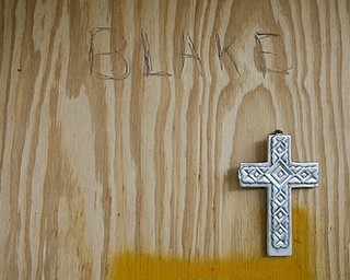 JESSICA M. KANALAS | THE VINDICATOR..A cross hangs beneath the words "BLAKE," is written with pen on the wood that covers the hole for Rik's front door.