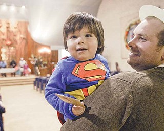 One-year-old Eli Clayman-Smith, held by his father, Matt Smith, is in the spirit of a “super” Purim on Wednesday night at Temple El Emeth in Liberty. The holiday, complete with costumes and funny hats, was celebrated with a reading from the Book of Esther on how the Jews in Persia defeated the evil Haman. Participants sounded “groggers” to boo the name of Haman when it was mentioned.