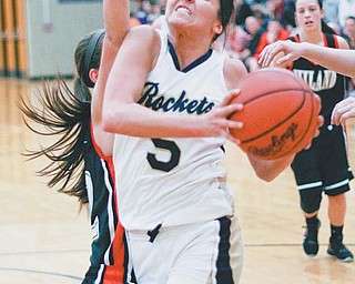 Lowellville’s Ashley Moore (5) charges past Berlin Hiland defender Jenica Schrock (12) on her way to the basket
during their Division IV regional semifinal Thursday at Massillon Perry High School. The Hawks’ defense and depth proved too much for the Rockets, who fell 47-37.