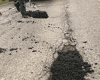 Brian Tidings, a worker with the Mahoning County Engineer’s office, tries to keep up with spring tasks by filling potholes with cold patch on Mahoning Avenue in North Jackson. County engineer employees have been busy fi lling potholes instead of plowing snow and salting roads, thanks to a mild winter season.