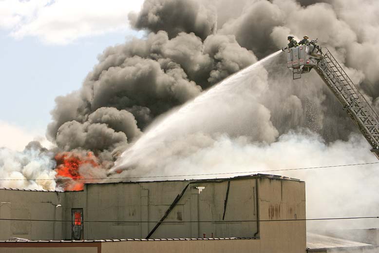 Youngstown firefighters spray water to control a blaze at an industrial building on the city’s lower North Side. The department was busy Monday with two simultaneous fires, this fire at 837 Madison Ave. and a smaller fire at a house at 23 Hilton Ave.