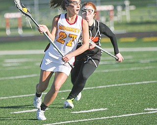 Cardinal Mooney’s Makenna Ozenghar, pursued by Orange defender Arianna Cerqueira, looks to pass during the first half of a lacrosse game Wednesday at Mooney High School. The Cardinals dominated the Lions, 16-0.