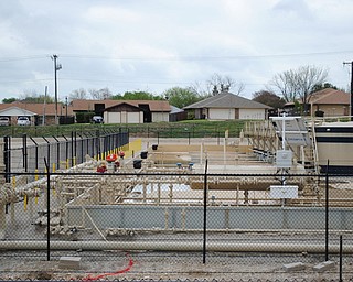 A drilling well pad sits in the foreground, just across the street from a regular neighborhood of Fort Worth, Texas.