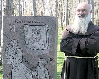 The Rev. Vit Fiala, a Franciscan friar at Shrine of Our Lady, Comforter of the Afflicted, stands beside an Iron Curtain Station of the Cross on shrine grounds. The sixth station is Veronica wiping the face of Jesus,
exemplified by a face on cloth; the Iron Curtain version depicts homelessness.