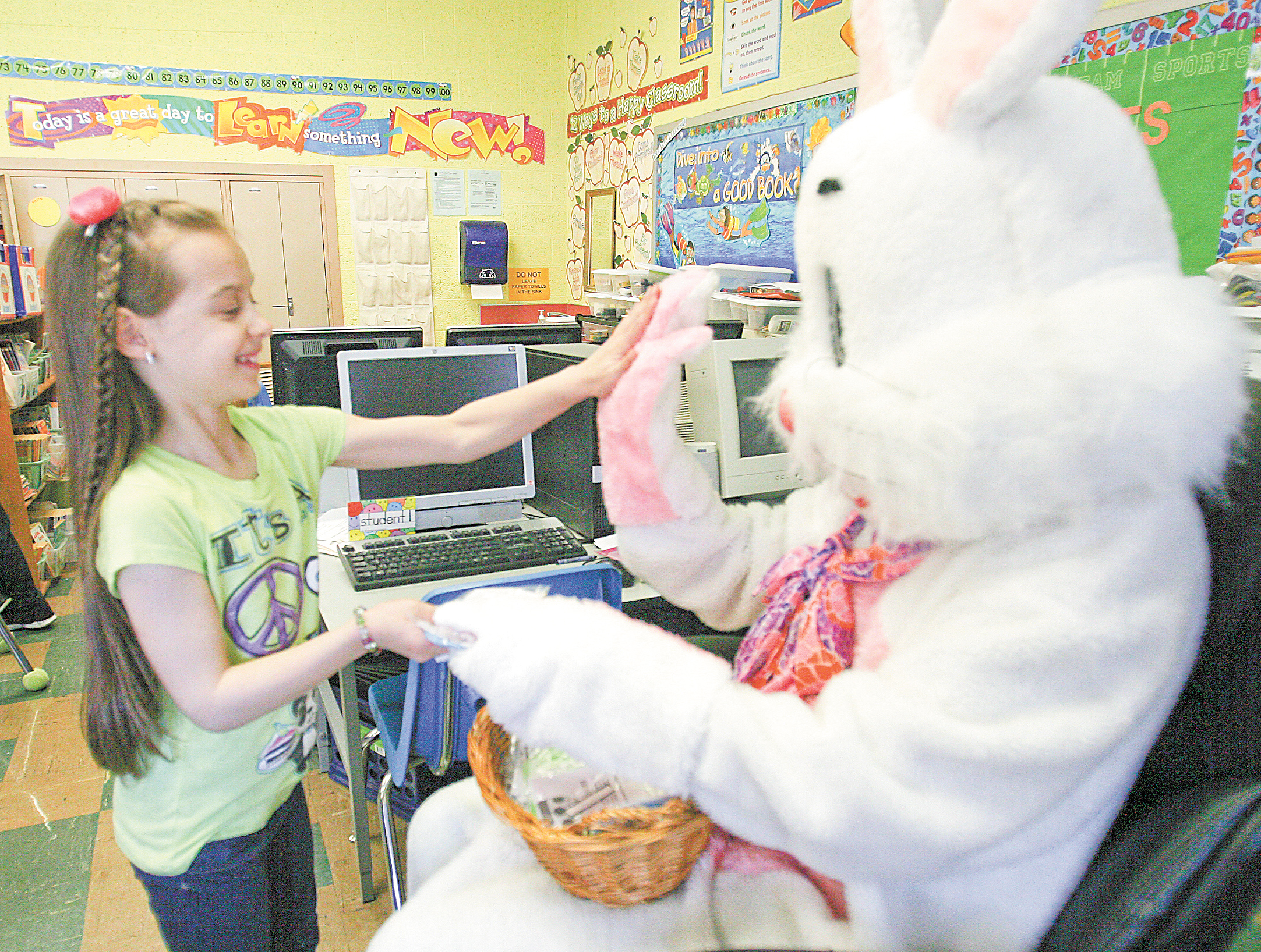Lily Raynish, a second-grader at Lloyd Elementary in Austintown, high-fives the Easter Bunny on Thursday as he visited each of the school’s classrooms. The visit is an annual event organized by the Lloyd Elementary Parent Teacher Association. Below, James Jones, a second-grader, shows off an Easter egg that he decorated during class Thursday. Lloyd students spent the day doing Easter crafts and meeting the Easter Bunny.