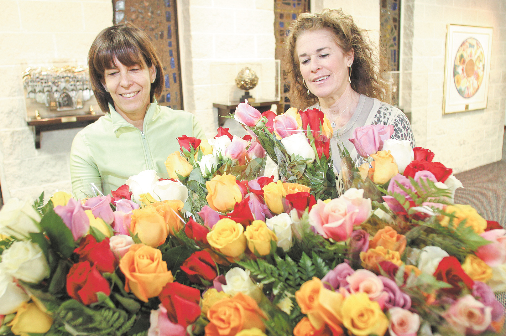 Debbi Grinstein, left, and Rochelle Miller, members of Temple El Emeth in Liberty, admire bundles of colorful and fragrant roses that will adorn Passover tables. Miller, chairwoman of the project for the temple Sisterhood, said the roses fundraiser began as a way to support Israeli entrepreneurs.