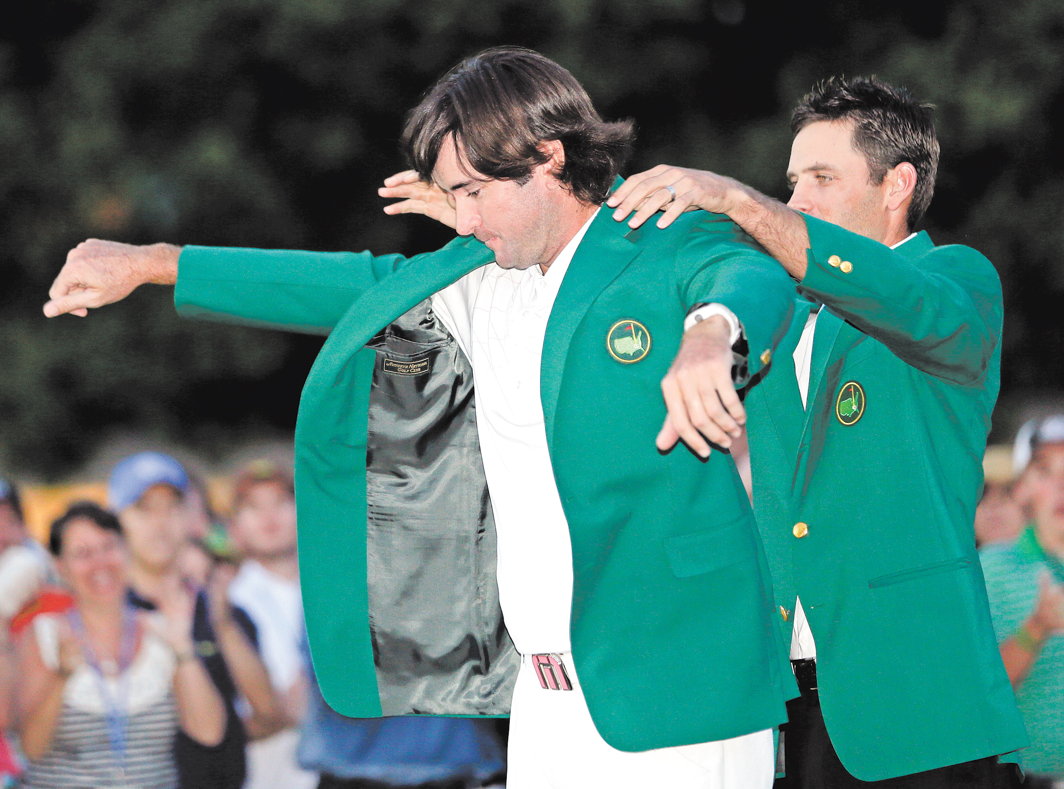 Charl Schwartzel, right, of South Africa, helps Bubba Watson put on the green jacket after winning the Masters golf tournament after a sudden-death playoff on the 10th hole Sunday in Augusta, Ga.