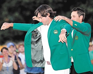 Charl Schwartzel, right, of South Africa, helps Bubba Watson put on the green jacket after winning the Masters golf tournament after a sudden-death playoff on the 10th hole Sunday in Augusta, Ga.