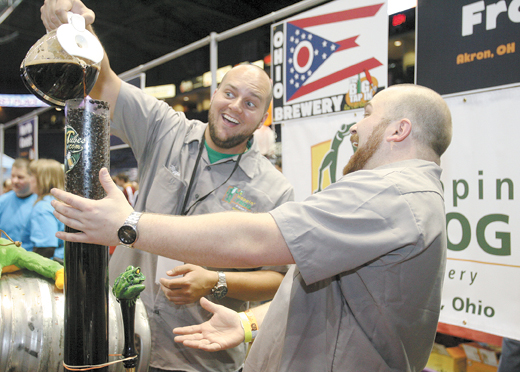 Bottlers Jeff Riggs and Dave Hoopes pour Italian roast coff ee into Hoppin’ Frogs signature Silk Porter to distribute at the Big Tap In craft beer festival Saturday at Covelli Centre.