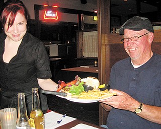 Heather Bornes hands Scott Long his burger for review.