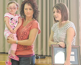 Madison Antal, 5, and her mom, Cristal Antal, both of Lordstown, left, presented an appreciation plaque Thursday to Poland Union Elementary students who raised funds to support Madison’s Make-A-Wish project. Make-A-Wish representative Kim Sazima, right, also was on hand to thank the students.