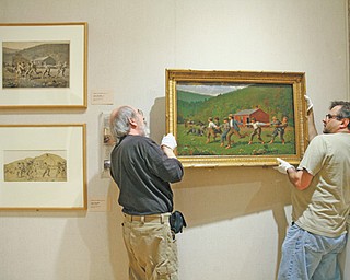 Butler Institute of American Art employees Ray Johnson, left, and Wayne Gruver hang the newly reframed painting “Snap the Whip” in a gallery at the museum Thursday.
