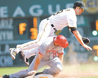 Pittsburgh Pirates second baseman Neil Walker falls over Cincinnati Reds’ Chris Heisey as he throws to first to complete the double play on a ground ball by Todd Frazier in the eighth inning of a game Sunday in Pittsburgh.