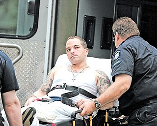 Ambulance personnel load Adam Carson, 29, into an ambulance after a two-hour standoff on Homestead Avenue. Carson is charged with two counts of bank robbery in Ashtabula County.