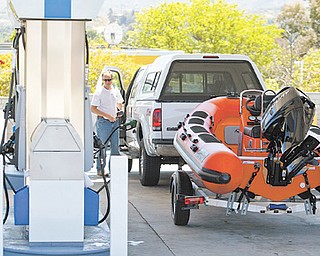 Travelers fill up at a gas station for an early start on the Memorial Day weekend traffic in Valencia, Calif. This year, economists and tourism experts are expecting only a small uptick in summer travelers. Gas prices are lower but still high enough to keep some Americans off the road.