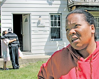 Melissa Watkins of Columbus takes time to reflect on the life of her cousin, Pako Lacey, 20, who was shot to death on the South Side earlier this week. Other family members embrace in the background in front of
the East Avondale Avenue home where police found his body.