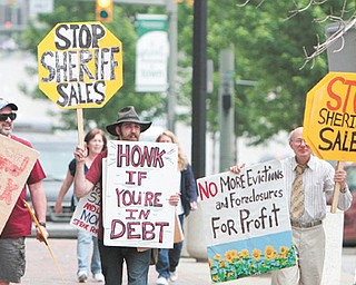 Sean O’Toole, left, Joshua Kessner and Jim Villani protest the Mahoning County sheriff ’s sale of homes that were to be auctioned off Tuesday. O’Toole and Kessner are members of Occupy Youngstown. The Occupy group says land banks should be used to hold and transfer property.