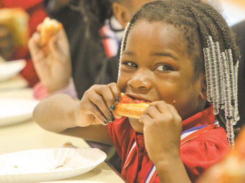 Cyra Cross, a member of the Principal’s Club, digs into a slice of pizza at the party.
