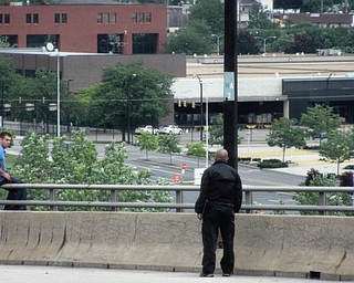 John Sylvester sits on the Market Street bridge Sunday as a police official talks with him. Sylvester was wanted for a stabbing incident in Boardman earlier in the day and fled to the bridge, where for four hours he kept police at bay with threats to jump before finally surrendering.
