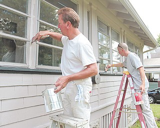 Mike Daugherty, left, and Ernie Avery of Avery Painting, spruce up a home in the city’s 7th Ward under Paint Youngstown, a city program that pays for minor repairs to homes that are facing code violations.