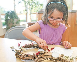 Sophie Herschmeyer, 6 of Youngstown, decorates a wreath Thursday during the Sobotka Polish Summer Solstice Celebration at Fellows Riverside Gardens. Traditional stories indicate that women released wreaths on the river as a way to help them find a suitor.