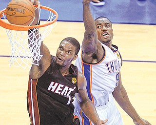 Miami Heat power forward Chris Bosh dunks the ball as Oklahoma City Thunder power forward Serge Ibaka defends during the first half of Game 2 of the NBA Finals on Thursday at the Chesapeake Energy Arena
in Oklahoma City. Bosh, who was back in the starting lineup for the first time since returning from an
abdominal injury, scored 16 points, to help lift the Heat over the Thunder, 100-96, and tie the series 1-1.