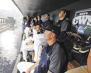 Kent State players wait in the dugout as heavy rain drenches the field before their College World Series
elimination baseball game against South Carolina on Wednesday in Omaha, Neb. The game was postponed
until noon today.