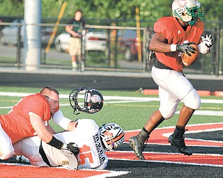 The helmet of Salem’s Matt Schuster (60), a member of the Mahoning/Columbiana All-Star team, comes off as he flattens Trumbull All-Star Zack Wilson of Howland to allow Mahoning teammate Nick Williams (1) of Fitch
to score a touchdown during the Jack Arvin All-Star Football Classic on Thursday at Girard’s Arrowhead Stadium.
Mahoning defeated Trumbull, 28-7.