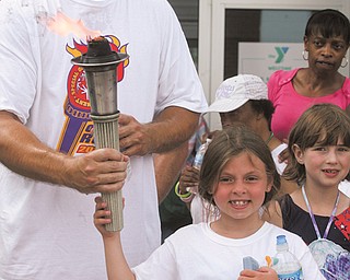 Boardman police officer John Gocala Jr. helps Brianna Hall, 8, of Boardman hold the “Flame of Hope” — the
Special Olympics torch — during the 2012 Ohio Law Enforcement Torch Run on Thursday. The run traveled
about three miles south on Market Street with stops at Meshel MASCO workshop, Davis Family YMCA and the
Boardman police station.