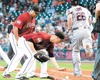 Astros first baseman Carlos Lee, left, and pitcher J.A. Happ watch a bunt by the Indians’ Derek Lowe during the
fifth inning of their game Sunday in Houston. The ball stayed fair, and Lowe reached first on the play.